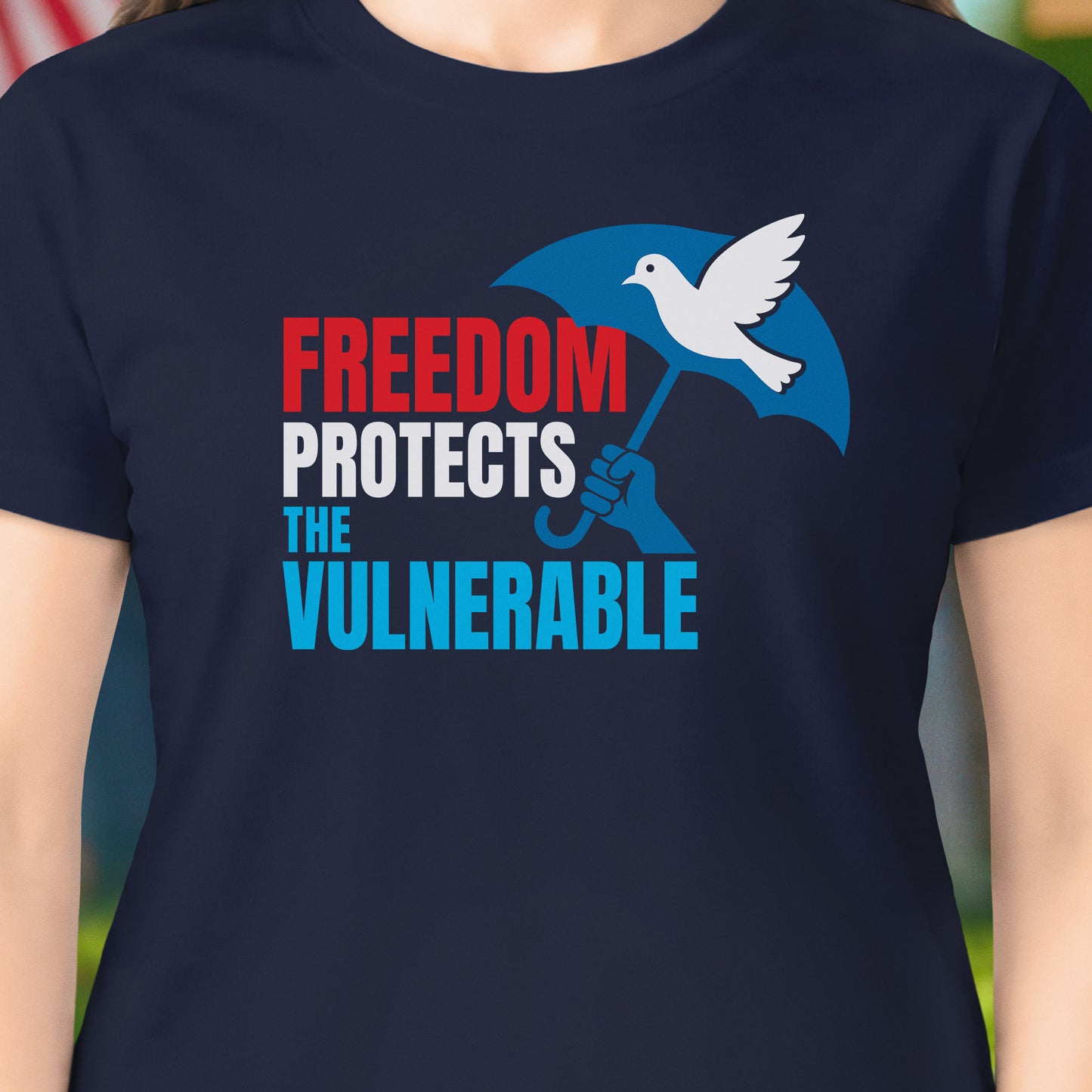 Navy blue t-shirt with a graphic and text 'Freedom Protects the Vulnerable' featuring a dove and hand holding an umbrella.